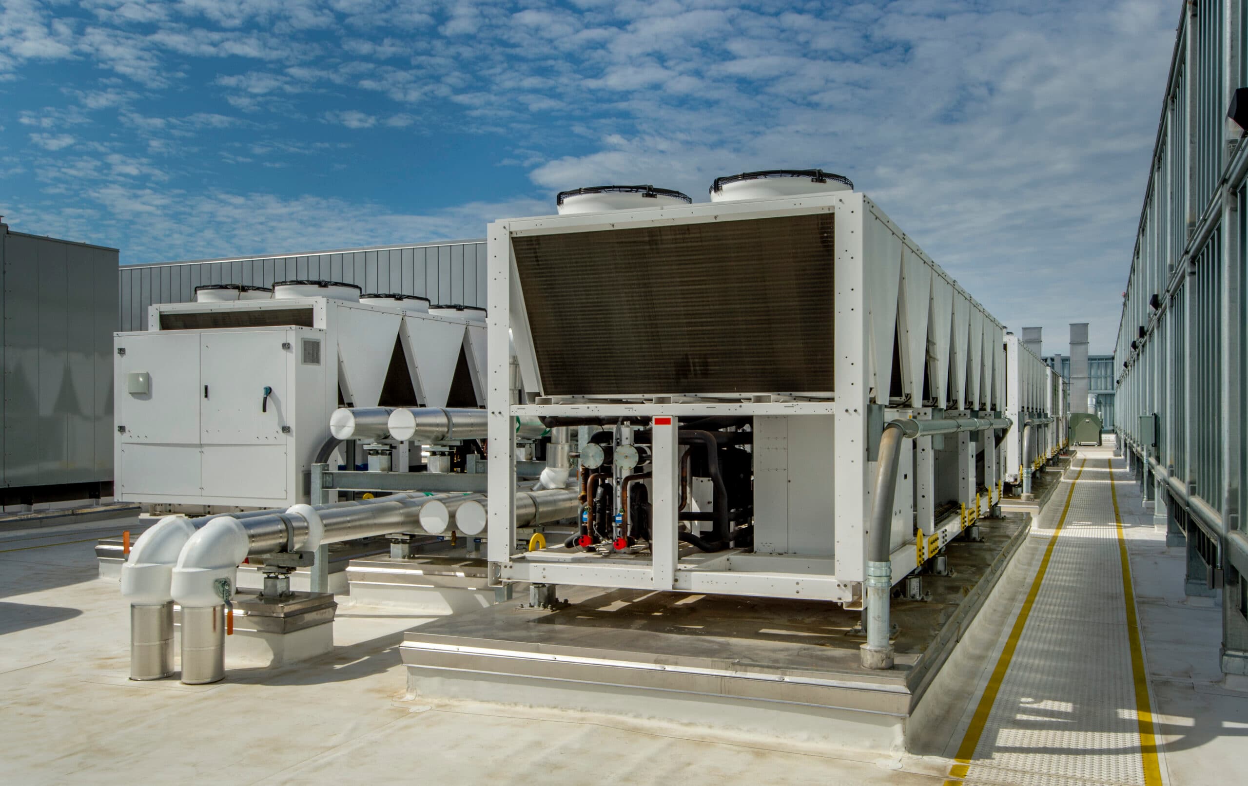 Modern industrial air-cooled chiller units on a commercial rooftop under a blue sky — Vinathermo commercial HVAC cooling solutions.
